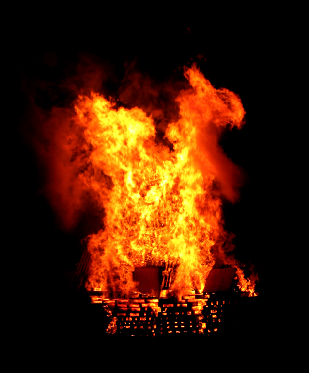 The burning pallets are stacked about 20 feet high